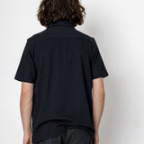 Person wearing a black shirt and dark pants against a white background
