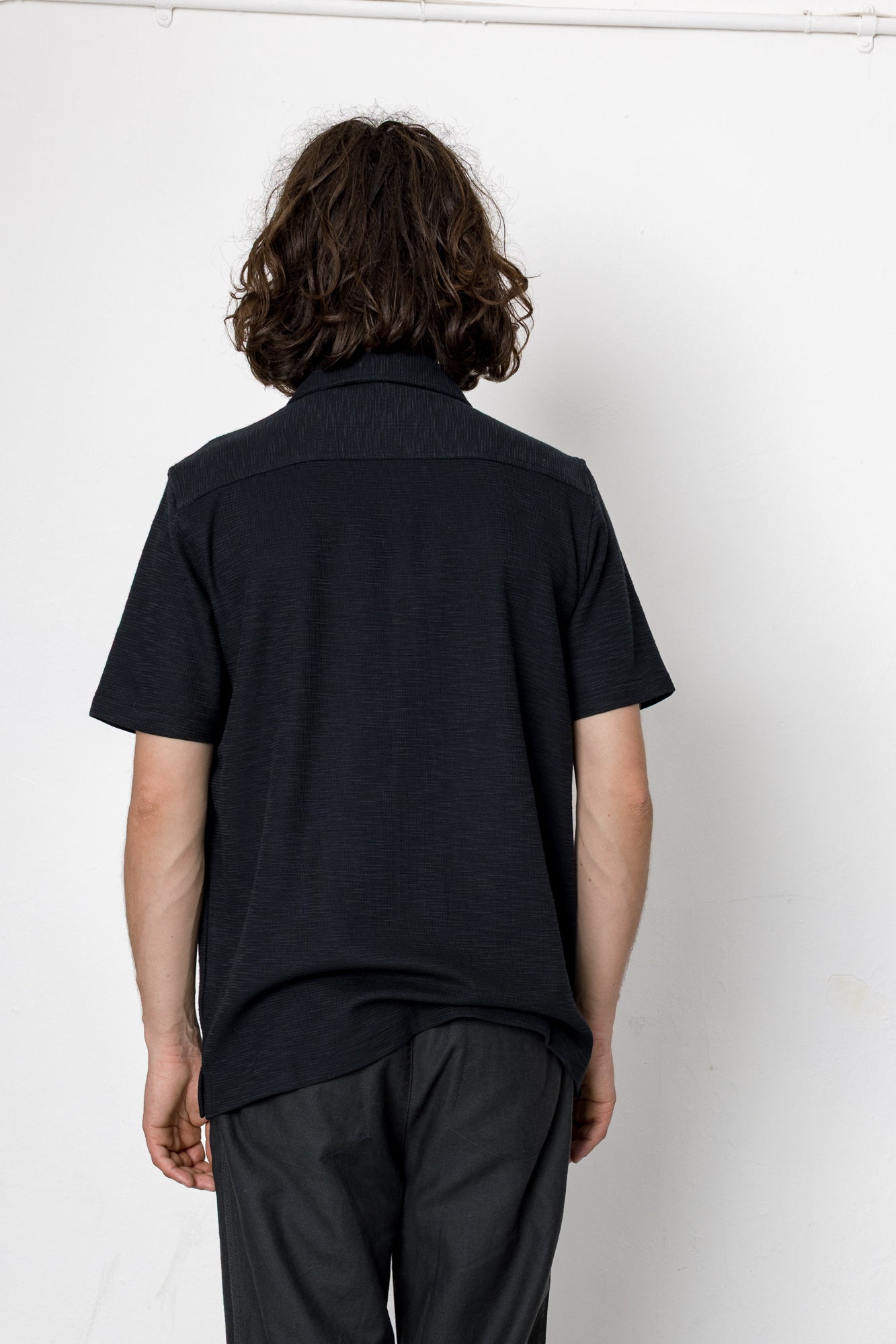 Person wearing a black shirt and dark pants against a white background