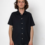 Man wearing a black short-sleeve button-up shirt against a white background