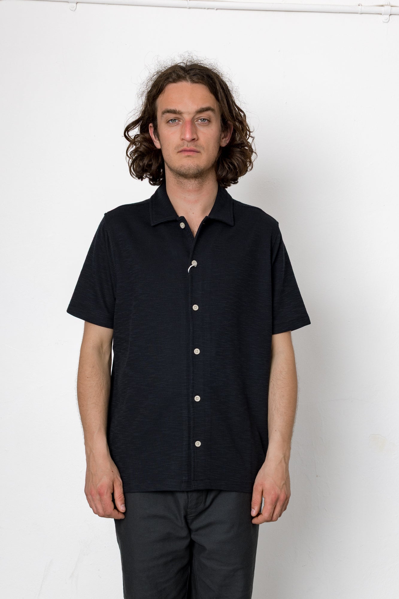 Man wearing a black short-sleeve button-up shirt against a white background