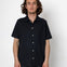 Man wearing a black short-sleeve button-up shirt against a white background