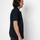 Man wearing a dark blue shirt and gray pants against a white background