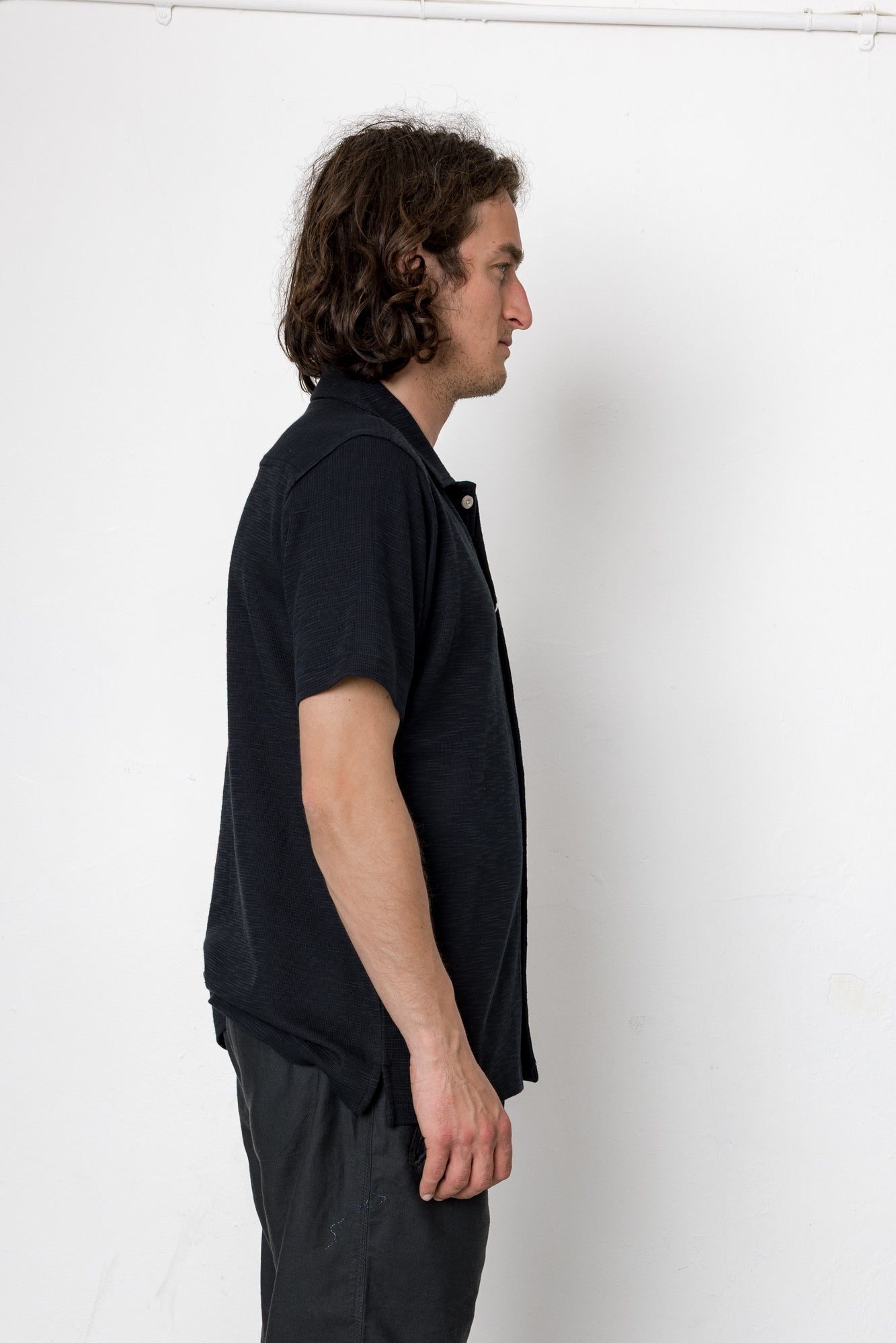 Man wearing a dark blue shirt and gray pants against a white background