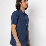 Man wearing a blue short-sleeve shirt against a white background