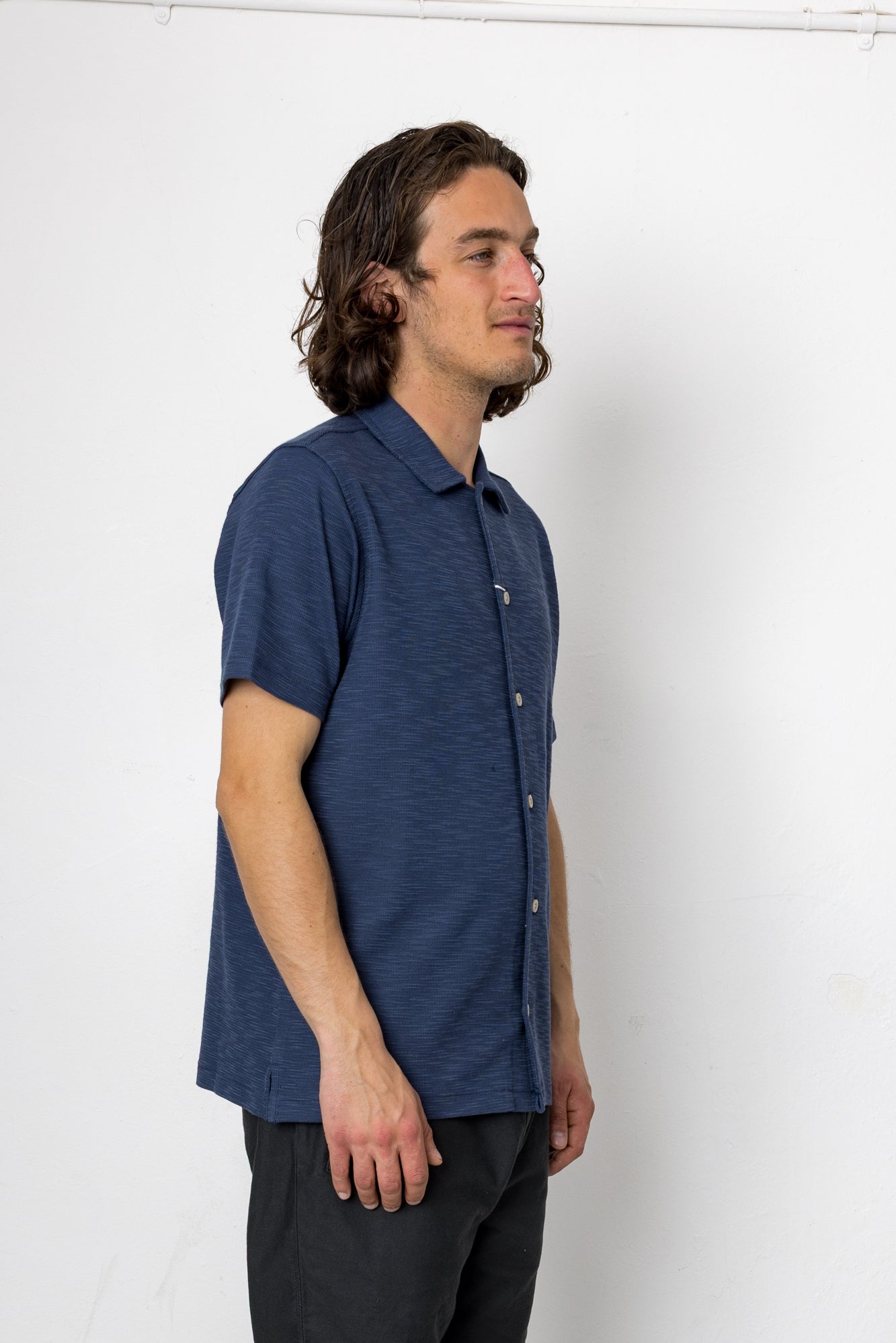 Man wearing a blue short-sleeve shirt against a white background