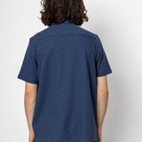 Person wearing a blue shirt and black pants against a white background