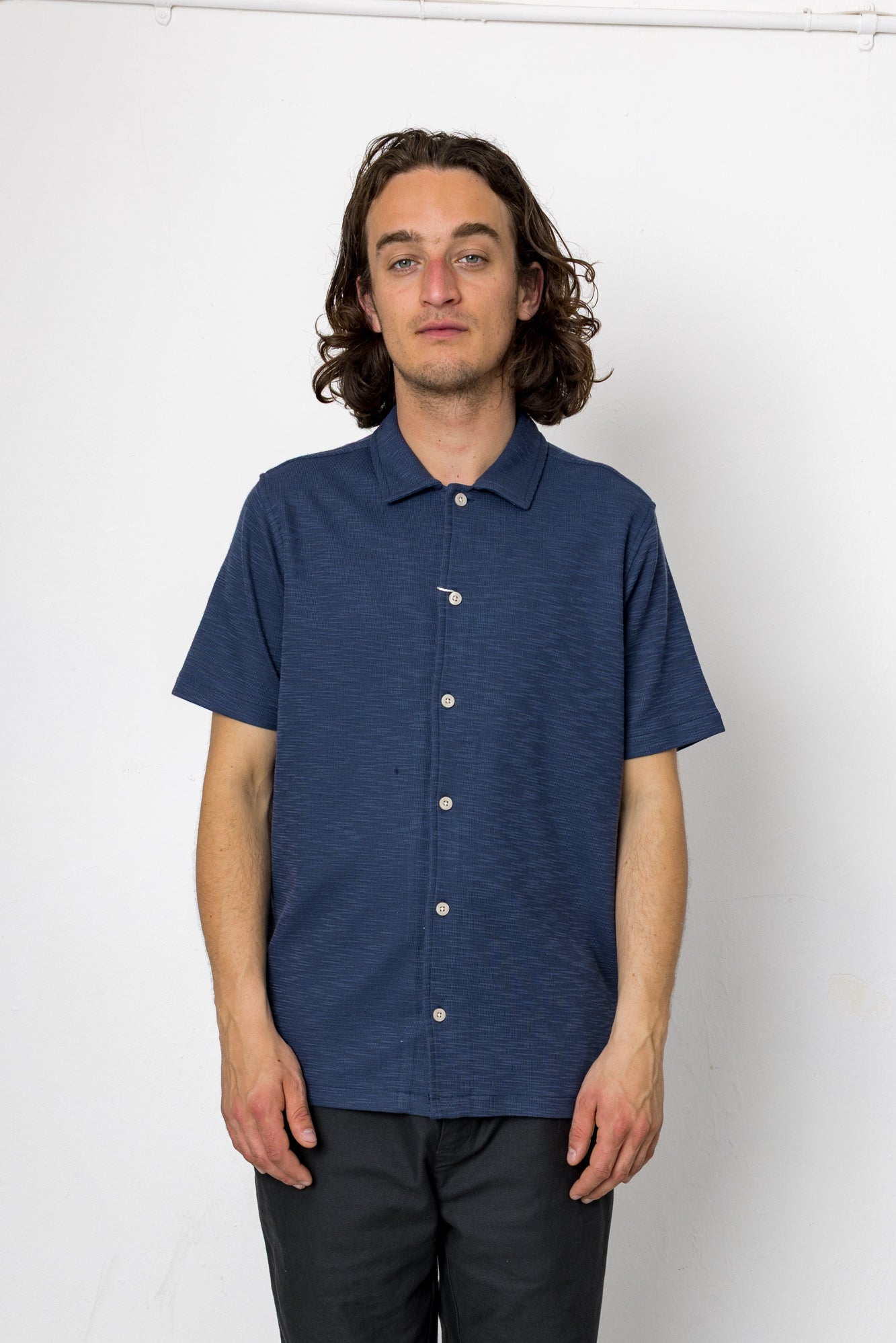 Man wearing a blue short-sleeve shirt against a white background