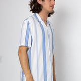 Man wearing a white shirt with blue stripes against a plain background