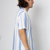 Man wearing a white shirt with blue patterns against a plain background