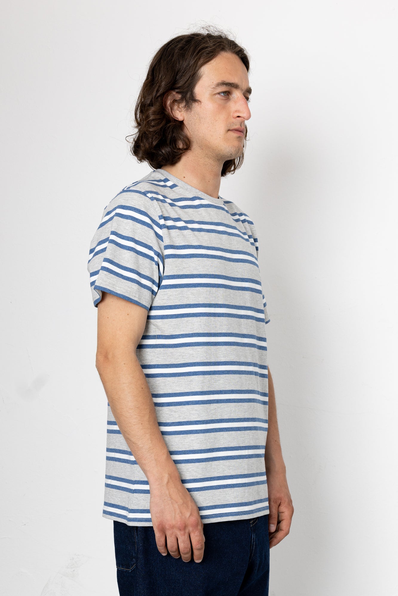 Man wearing a blue and gray striped t-shirt against a white background