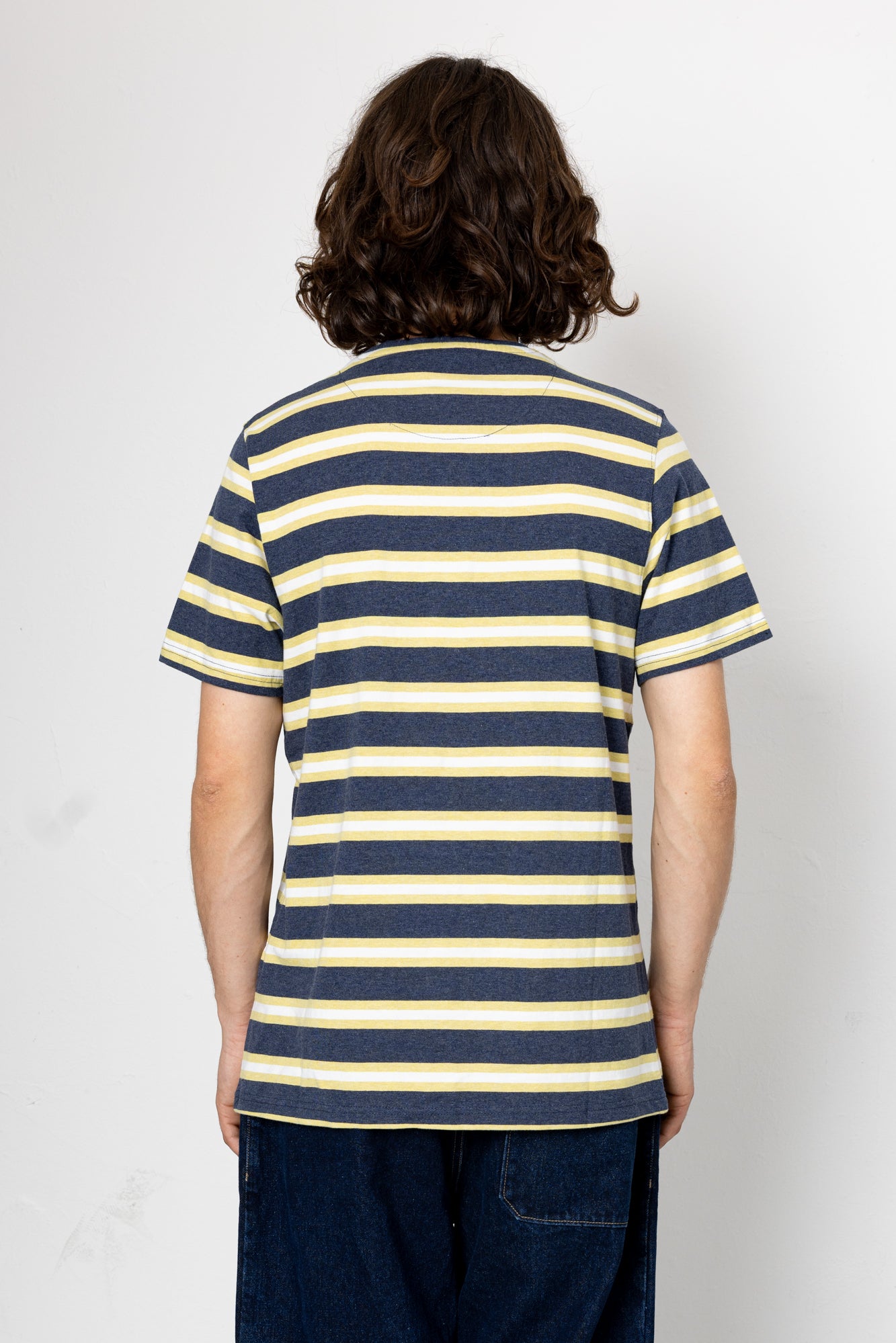 Person wearing a navy and yellow striped shirt against a white background