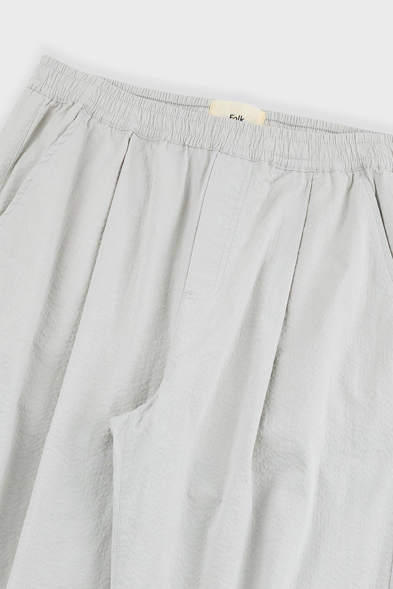Light gray pants with a brand label on a light gray background