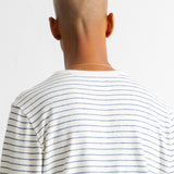 Rear view of a bald man wearing a white long-sleeve t-shirt with thin blue horizontal stripes, set against a plain white background.