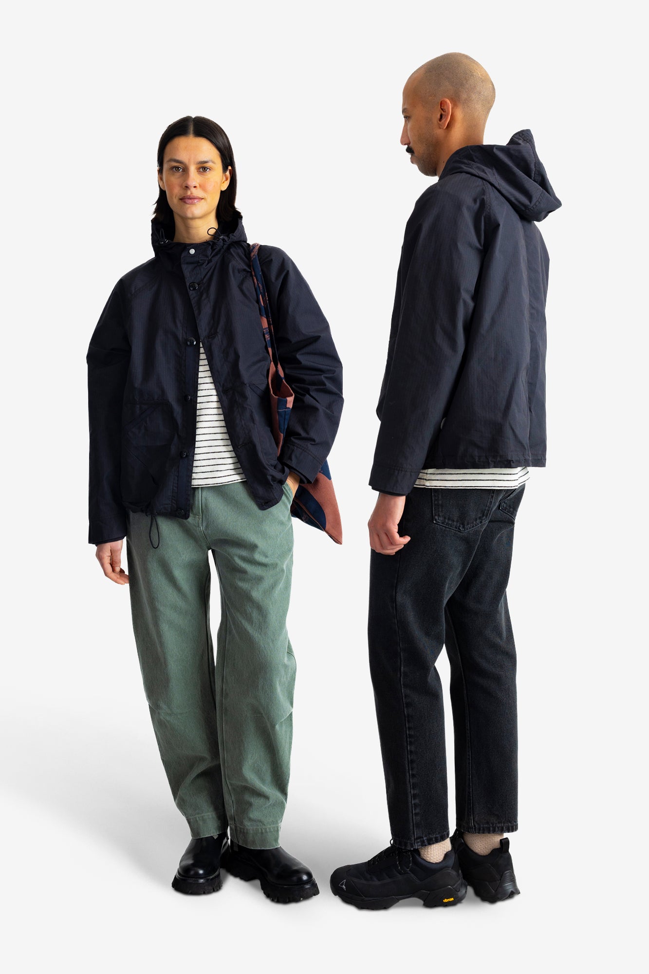 A man and a woman modeling a dark navy hooded jacket, shown from the front and back against a light gray studio background.