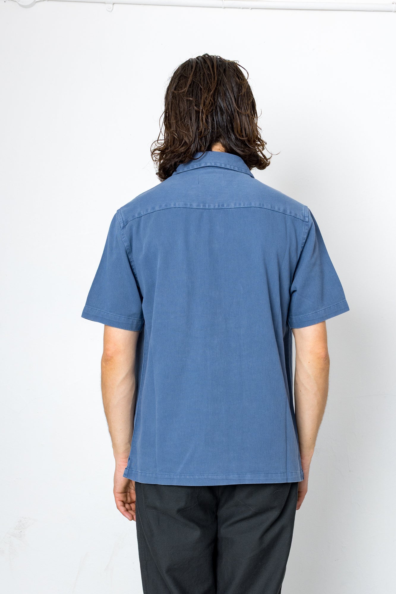 Person wearing a blue shirt from behind on a white background