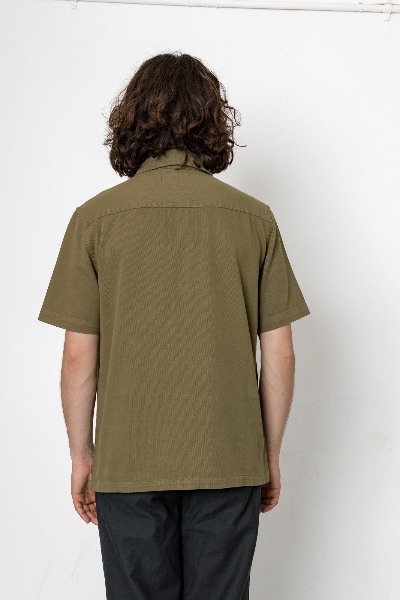Person wearing an olive green shirt against a white background