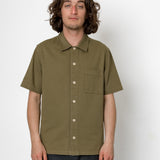 Man wearing an olive green short-sleeve shirt against a white background