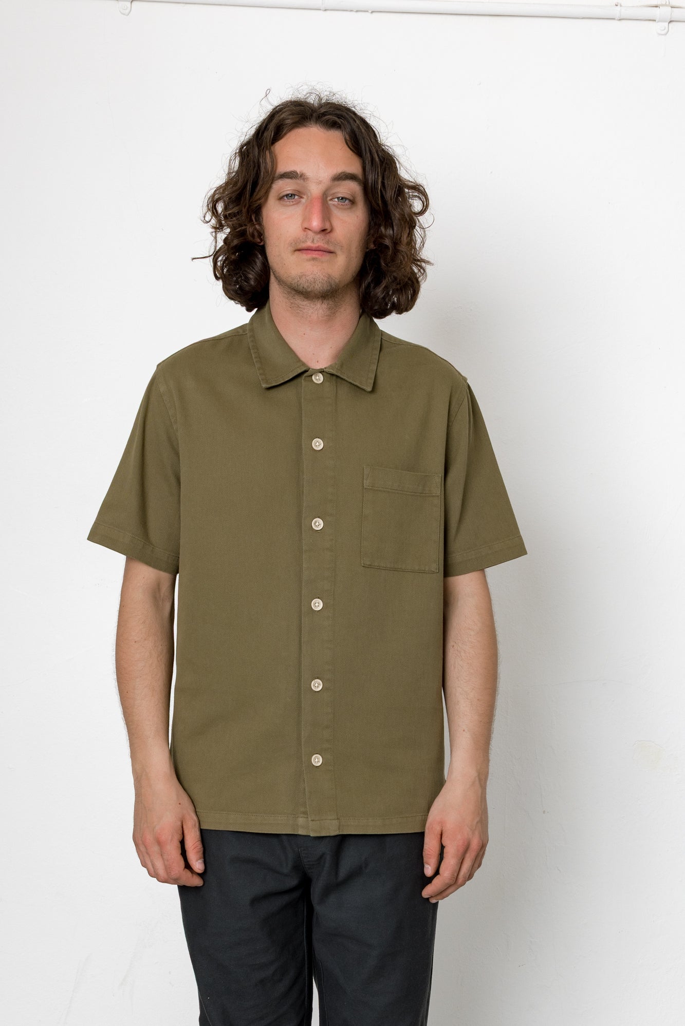 Man wearing an olive green short-sleeve shirt against a white background