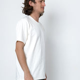 Man wearing a plain white t-shirt against a white background