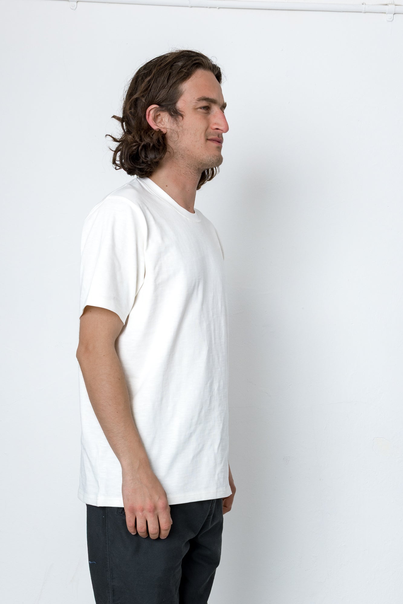 Man wearing a plain white t-shirt against a white background