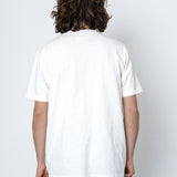 Person wearing a white t-shirt against a light grey wall