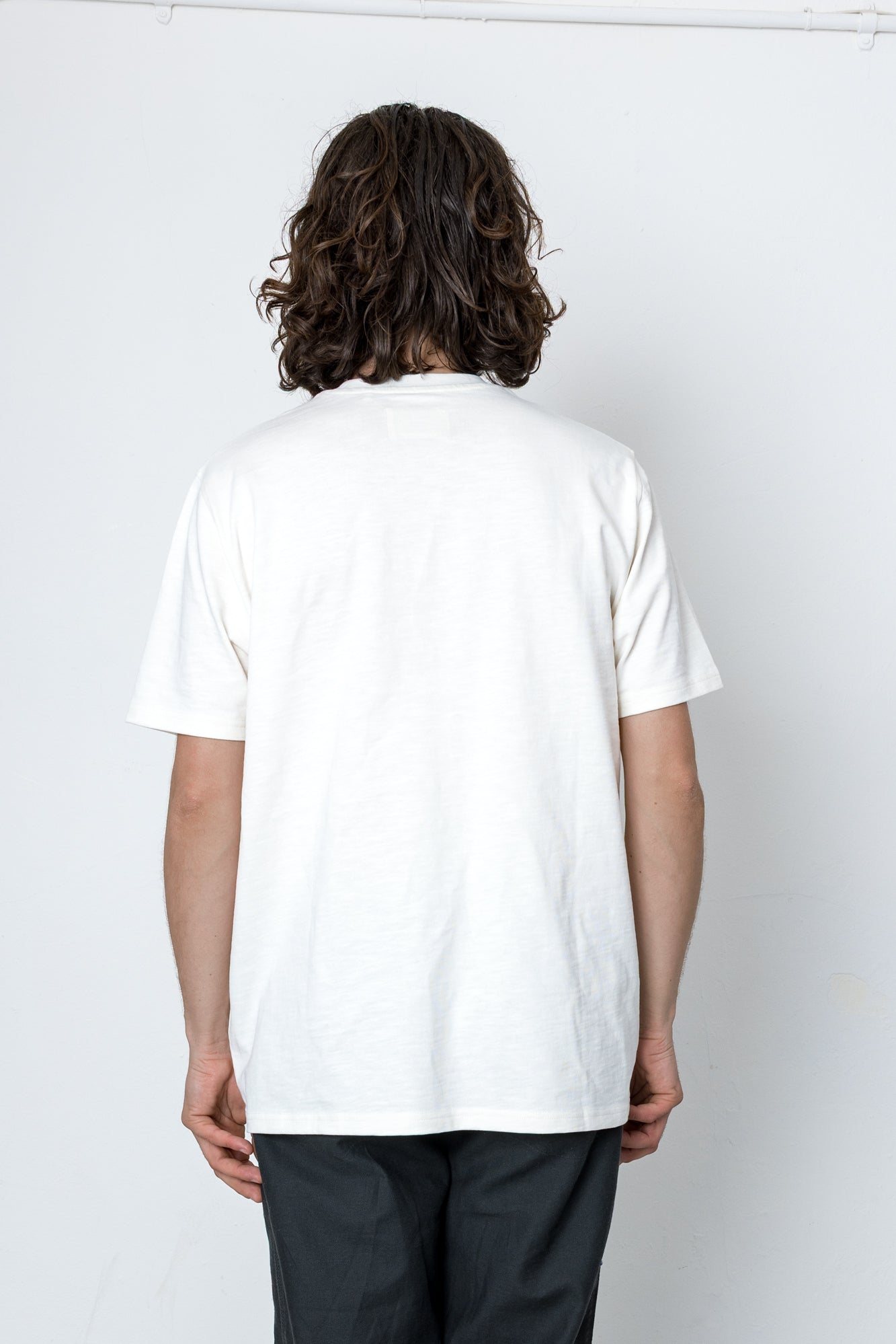 Person wearing a white t-shirt against a light grey wall