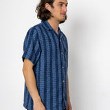 Man wearing a blue patterned shirt against a white background