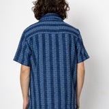 Person wearing a blue patterned shirt against a white background