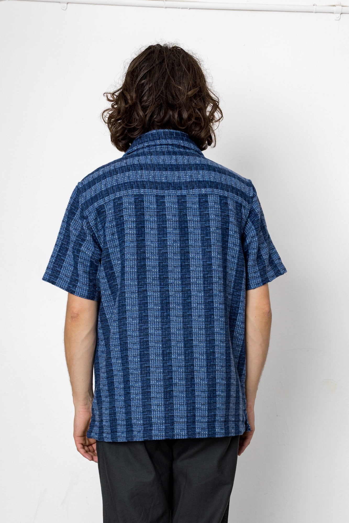 Person wearing a blue patterned shirt against a white background