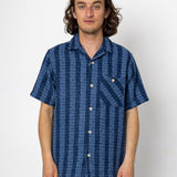 Man wearing a blue patterned shirt against a white background