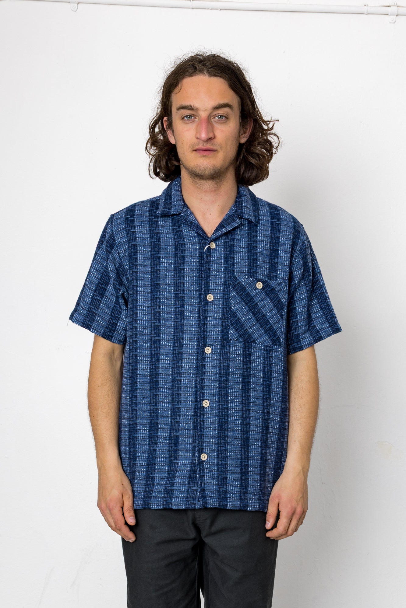 Man wearing a blue patterned shirt against a white background