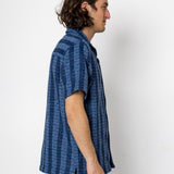 Man wearing a blue patterned shirt against a white background