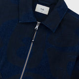 Close-up of a dark blue jacket with a zipper and 'Folk' label on a light gray background