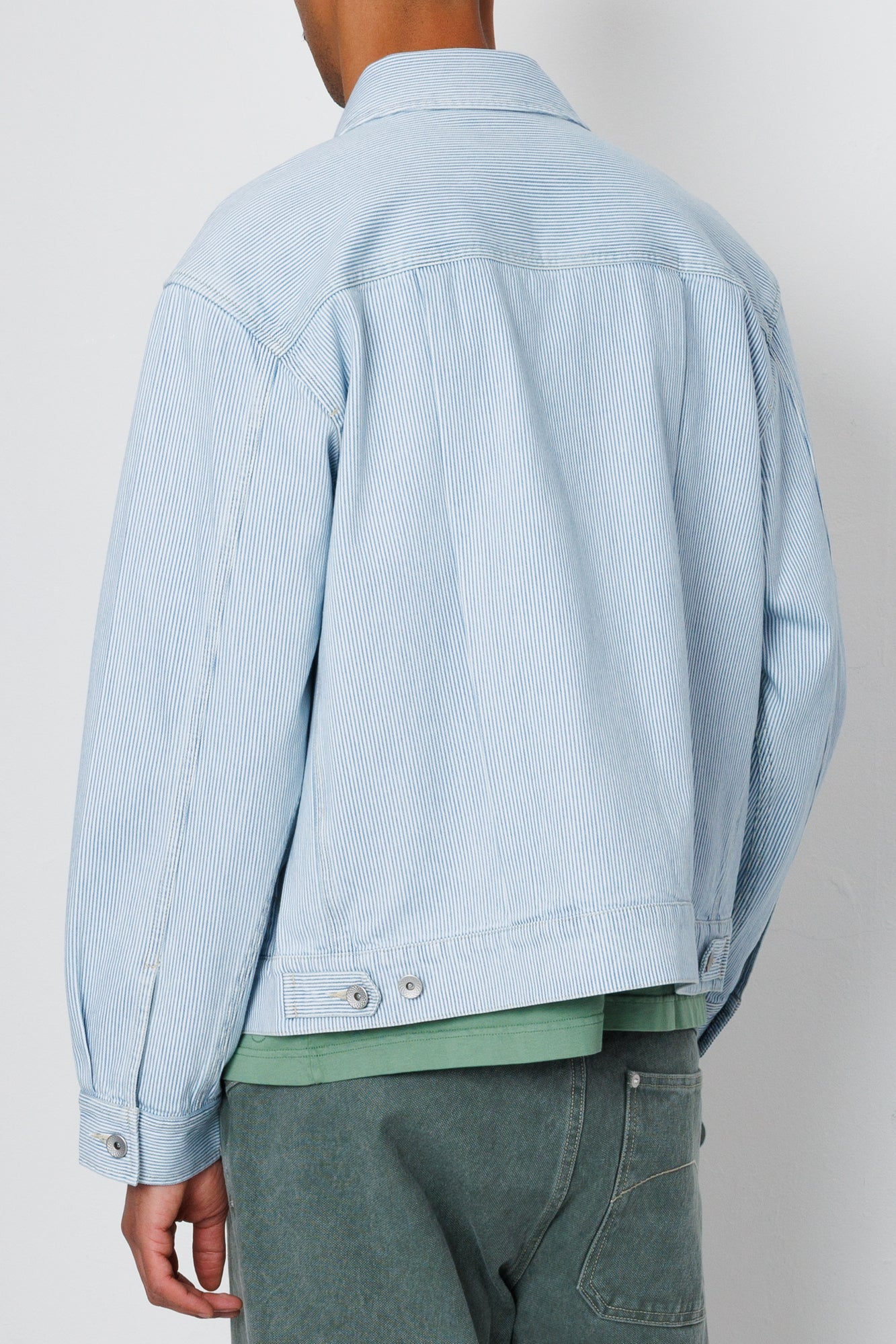 Light blue denim jacket worn by a person on a plain background