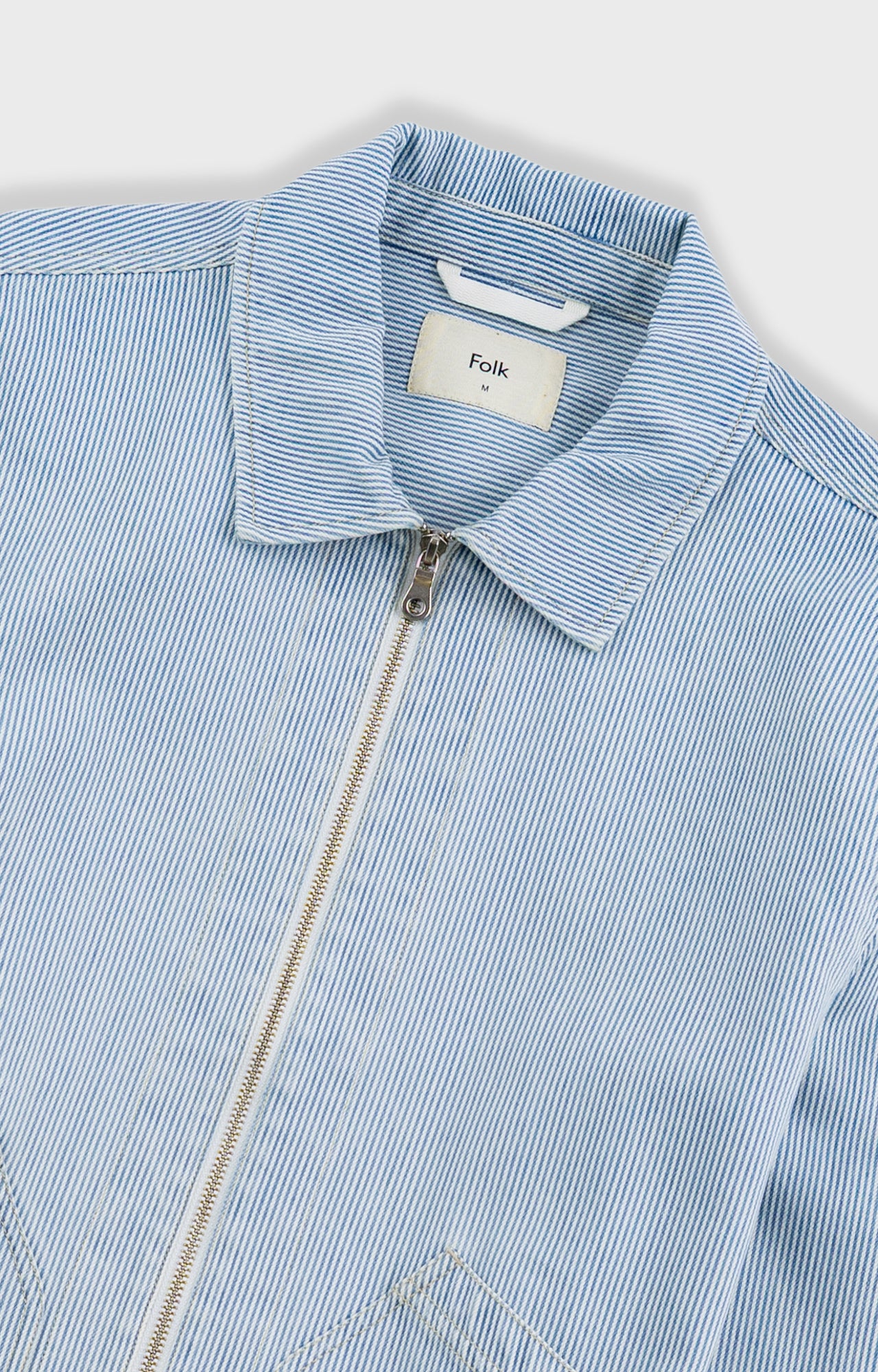 Light blue striped shirt with a brand label on a white background