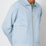 Man wearing a light blue corduroy jacket with a zipper on a plain background