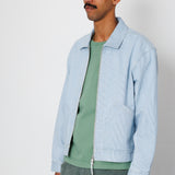 Man wearing a light blue jacket over a green shirt on a white background