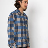 Man wearing a blue and gray checkered shirt against a white background