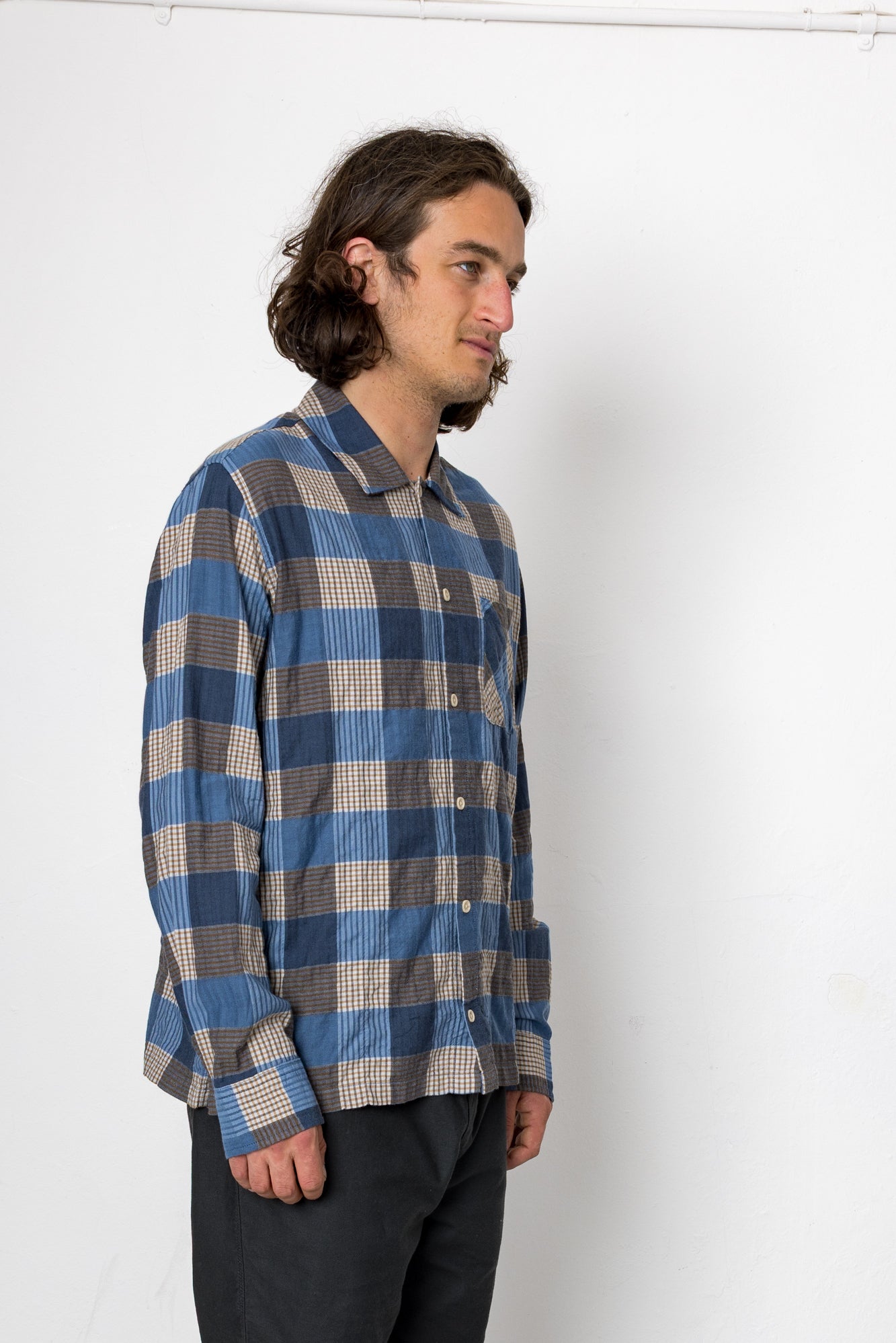 Man wearing a blue and gray checkered shirt against a white background