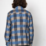 Person wearing a blue and brown plaid shirt against a white background