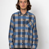 Person wearing a blue and gray plaid shirt against a white background