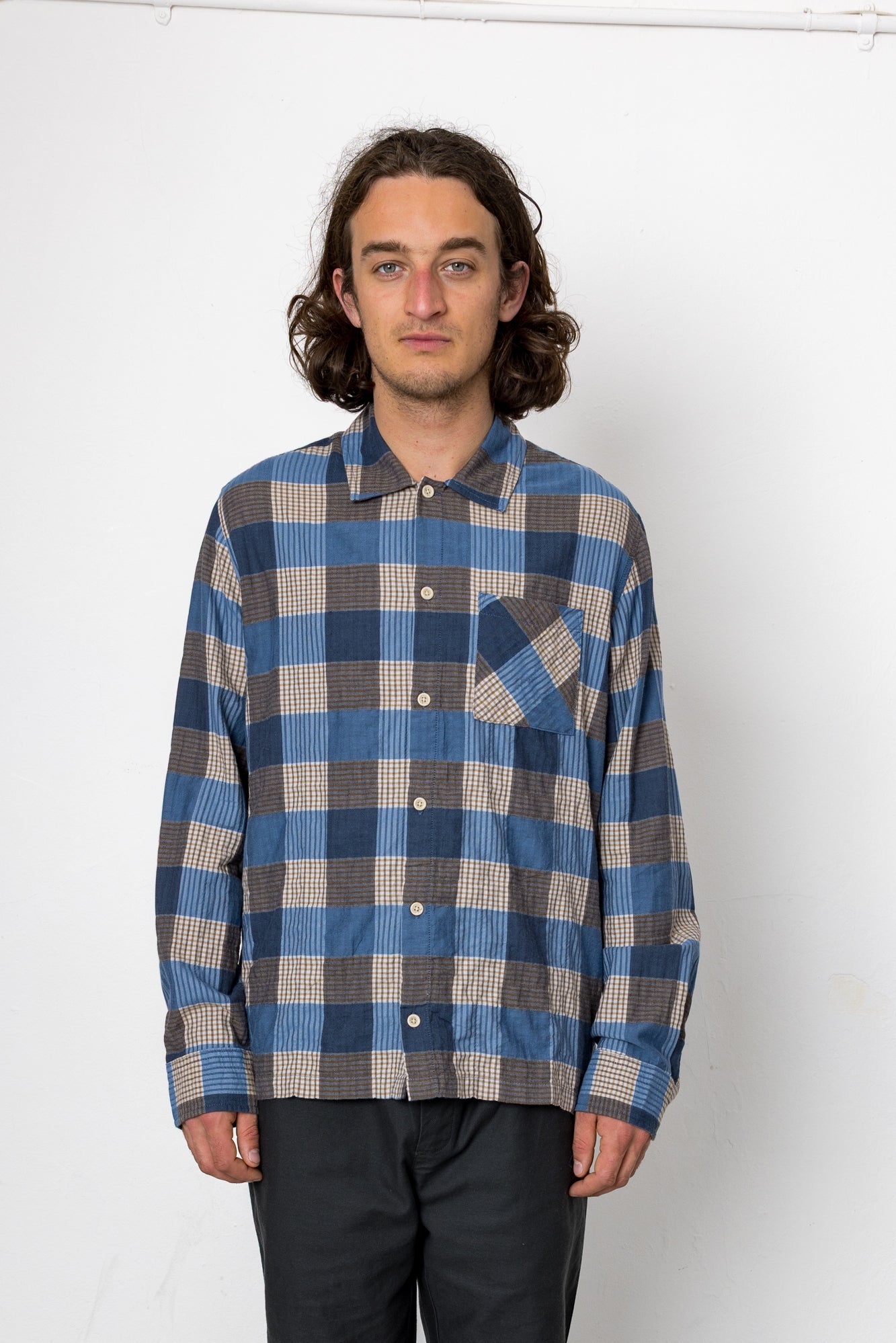 Person wearing a blue and gray plaid shirt against a white background