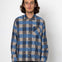 Person wearing a blue and gray plaid shirt against a white background