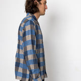Person wearing a blue and gray checkered shirt against a white background