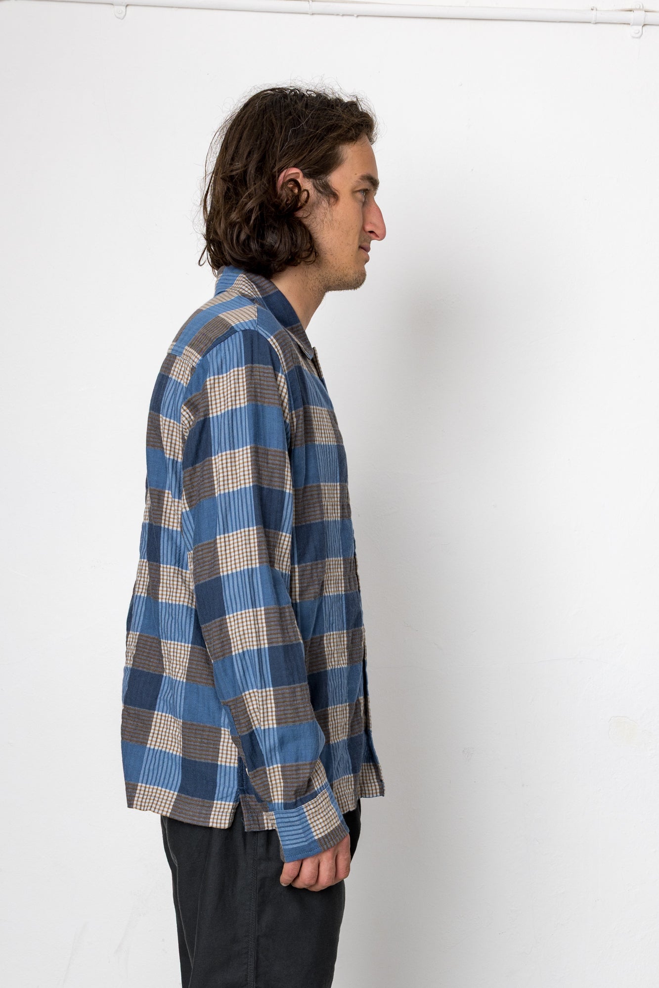 Person wearing a blue and gray checkered shirt against a white background