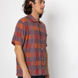 Man wearing a plaid shirt standing against a white background
