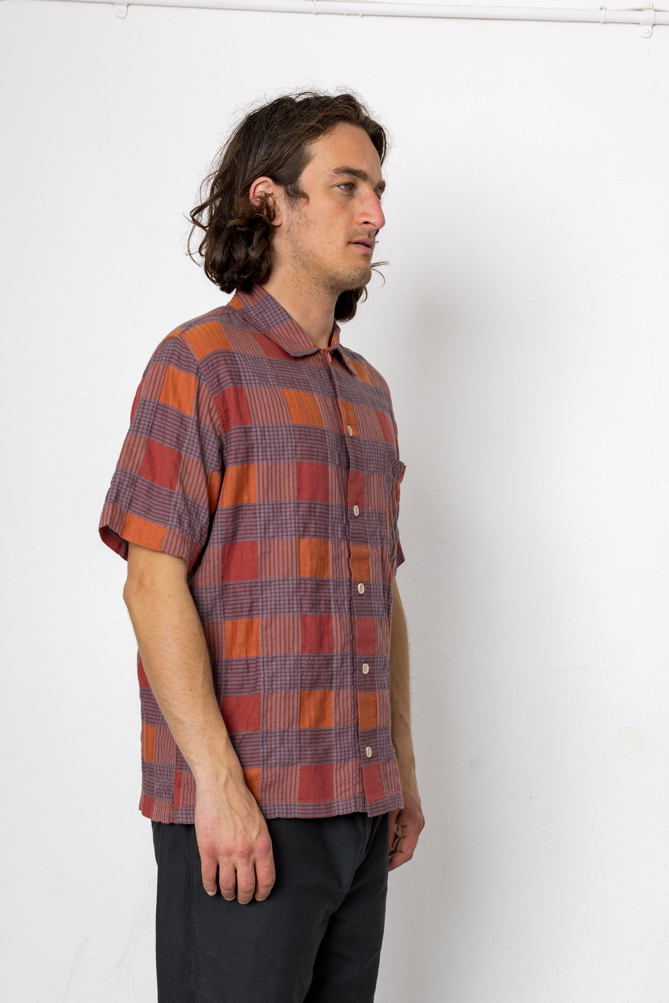 Man wearing a plaid shirt standing against a white background