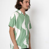 Man wearing a green and white patterned shirt against a plain background