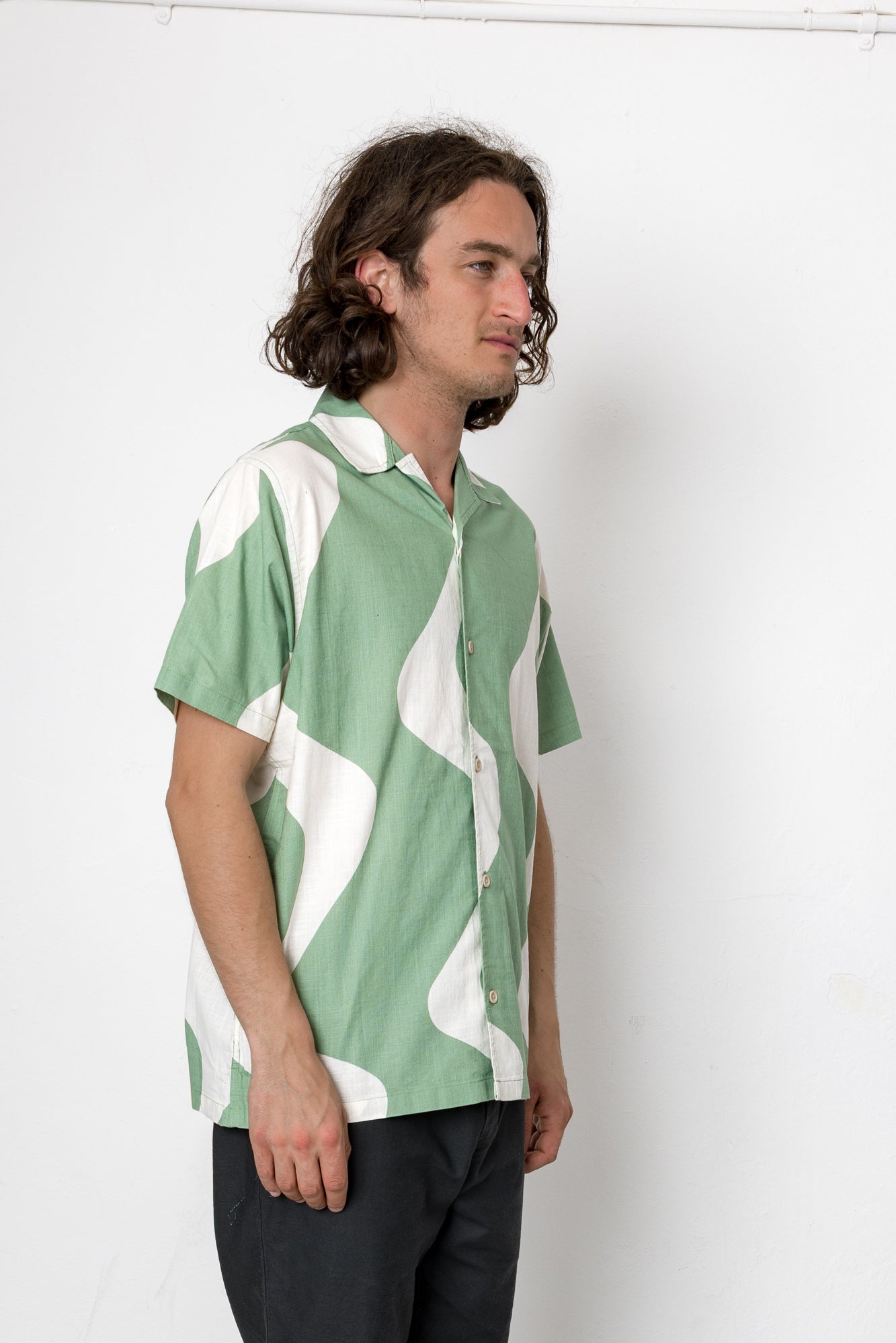 Man wearing a green and white patterned shirt against a plain background