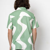 Person wearing a green and white patterned shirt against a white background